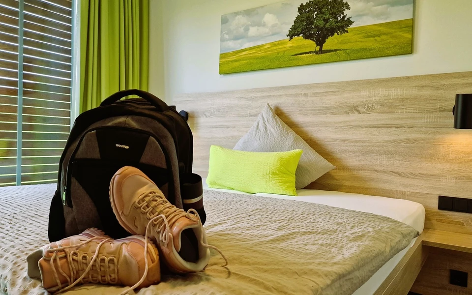 Zimmer im Hotel Fünf10 mit Wanderschuhen und Rucksack auf dem Bett