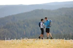 Zwei sportlich gekleidete Personen mit Speed Hiking-Ausrüstung vor einer Bergkulisse